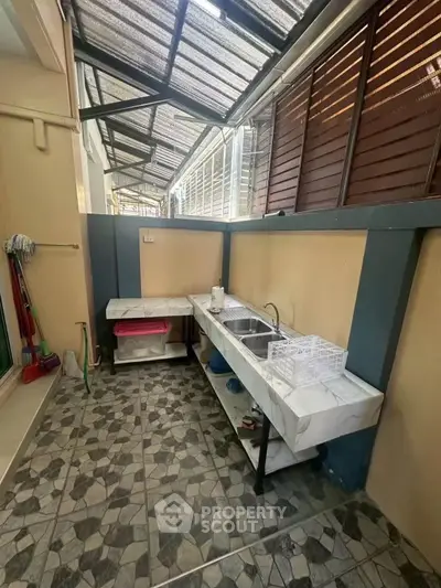 Charming outdoor kitchen area with tiled flooring and ample counter space, perfect for entertaining.