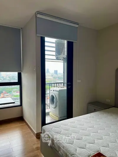Modern bedroom with balcony view and washing machine, featuring sleek design and ample natural light.