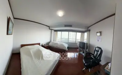 Spacious bedroom with two beds and city view, featuring hardwood floors and a comfortable office chair.