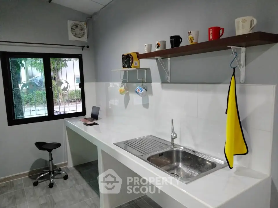 Modern kitchen with sleek countertops and open shelving, featuring a stylish sink and window view.
