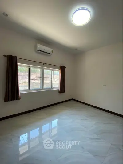 Spacious empty room with large window and air conditioning, perfect for customization.