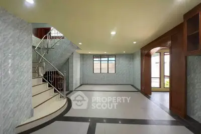 Spacious modern living room with elegant staircase and large window, perfect for family gatherings.