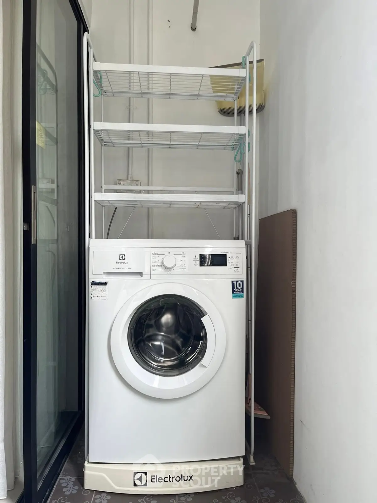 Compact laundry area with Electrolux washing machine and storage shelves.