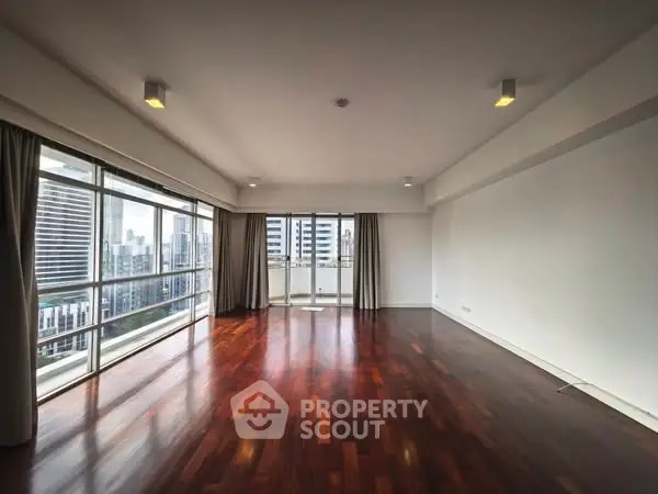 Spacious living room with hardwood floors and city view balcony access.
