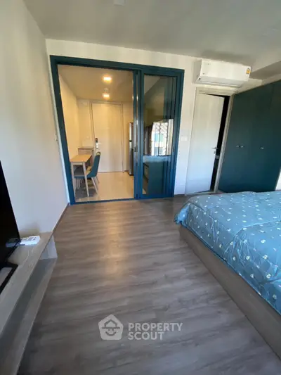 Modern bedroom with wooden flooring and blue accents, featuring a cozy bed and air conditioning.