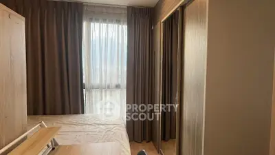 Cozy bedroom with large window and mirrored wardrobe in modern apartment.