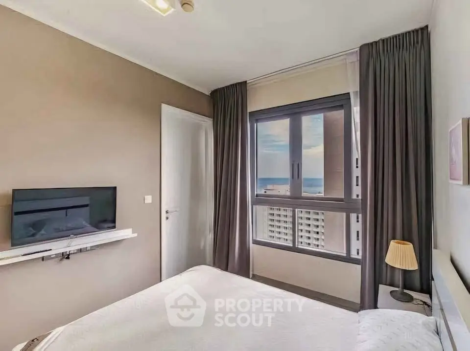 Modern bedroom with sea view and wall-mounted TV in high-rise apartment.
