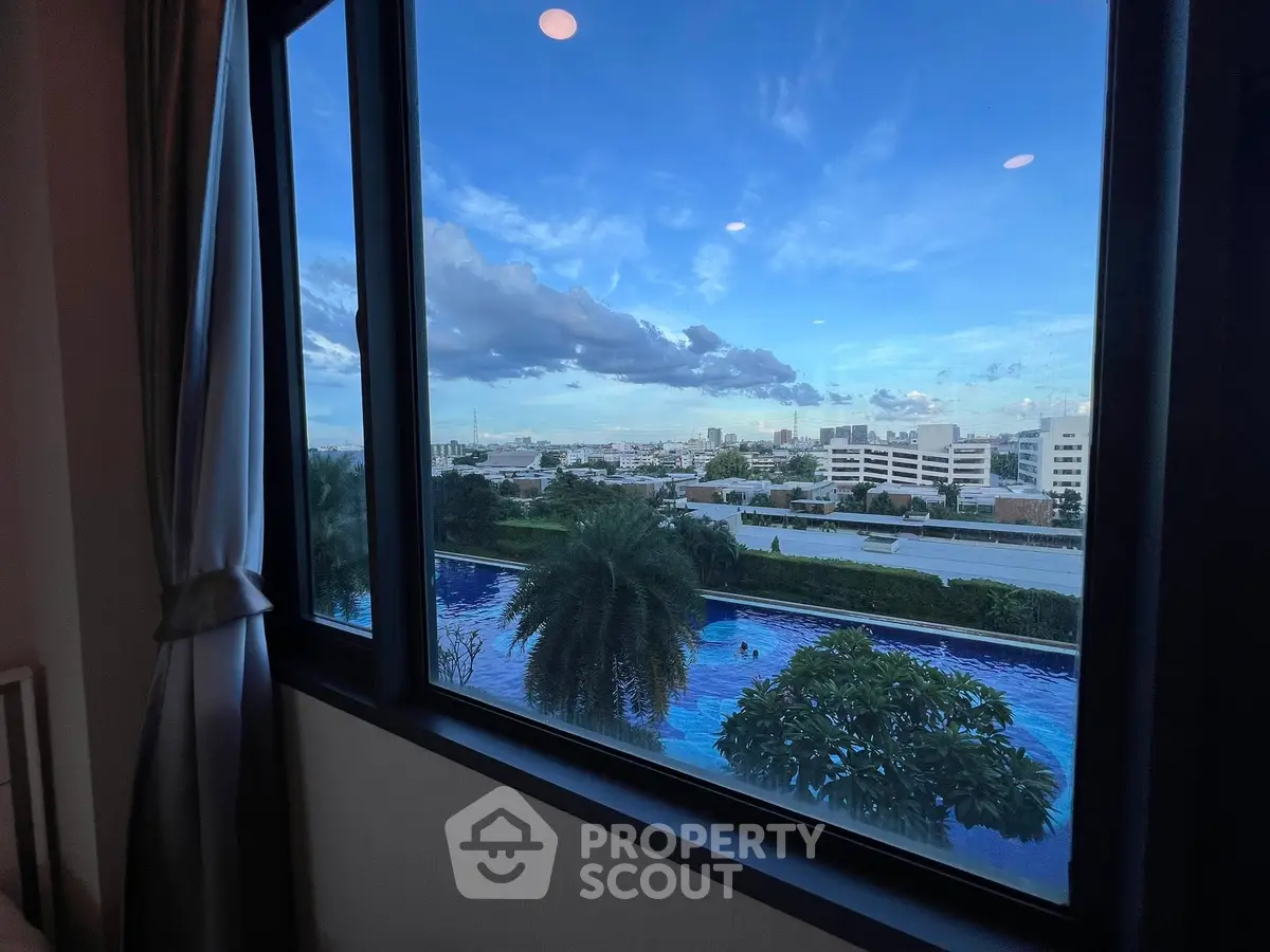 Stunning pool view from a high-rise apartment window with cityscape backdrop.