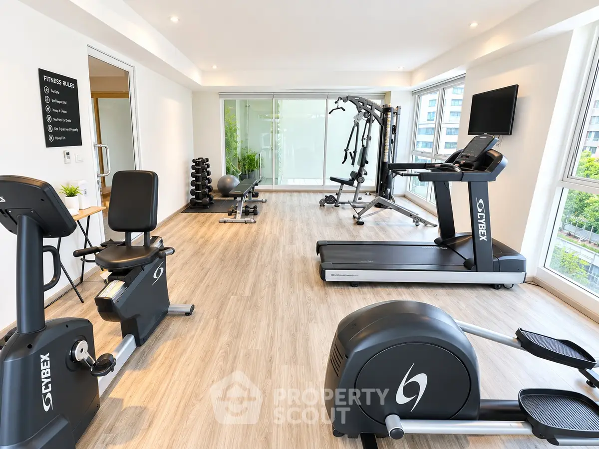 Modern gym with state-of-the-art equipment and large windows offering a bright and inviting workout space.