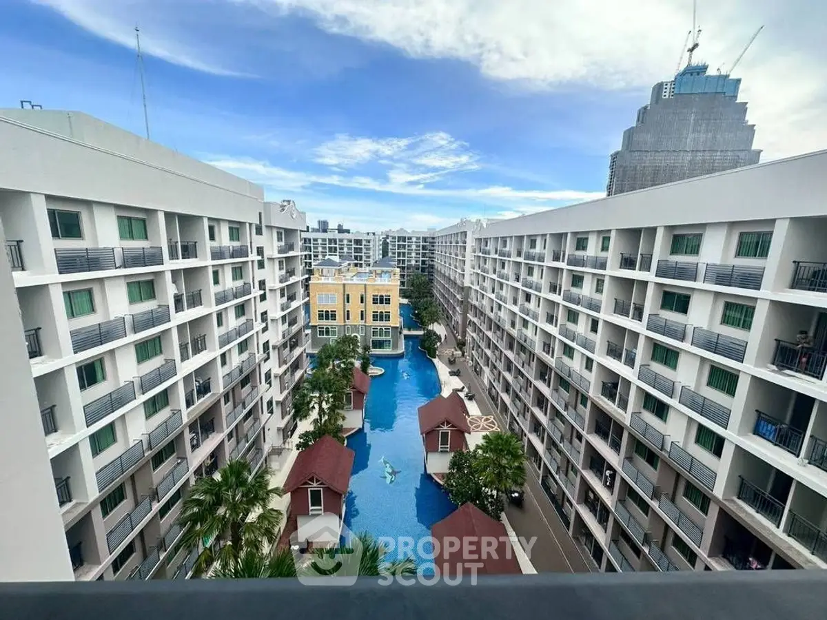 Stunning aerial view of modern apartment complex with central pool and lush greenery.