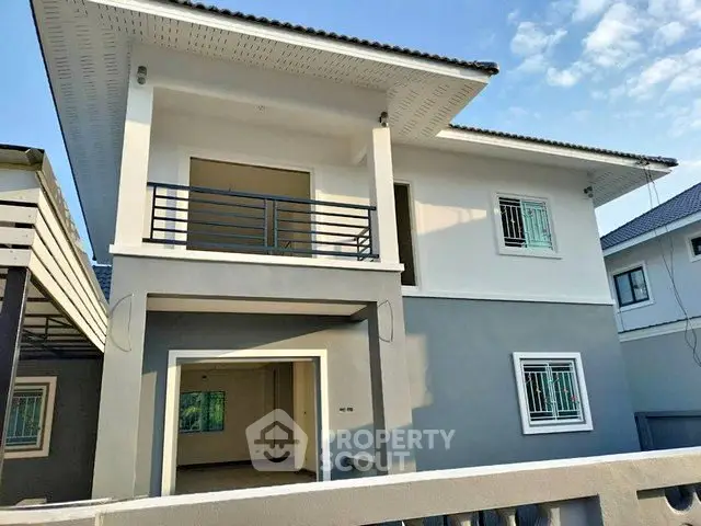 Modern two-story house with balcony and sleek exterior design in a suburban neighborhood.
