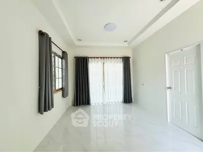 Spacious empty room with large windows and elegant curtains, perfect for customization.