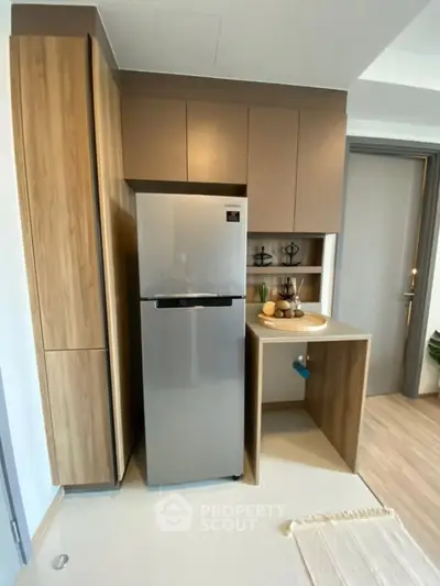 Modern kitchen with sleek cabinetry and stainless steel fridge in compact layout.