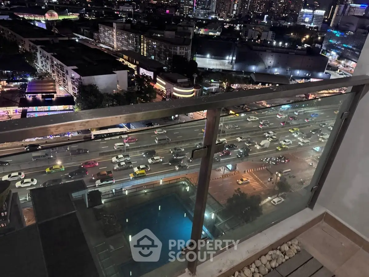 Stunning city view from high-rise balcony overlooking bustling streets at night.