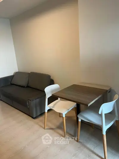 Modern living room with sleek sofa and compact dining set, perfect for urban living.