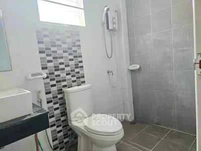 Modern bathroom with sleek tiles and shower heater, perfect for a cozy home.
