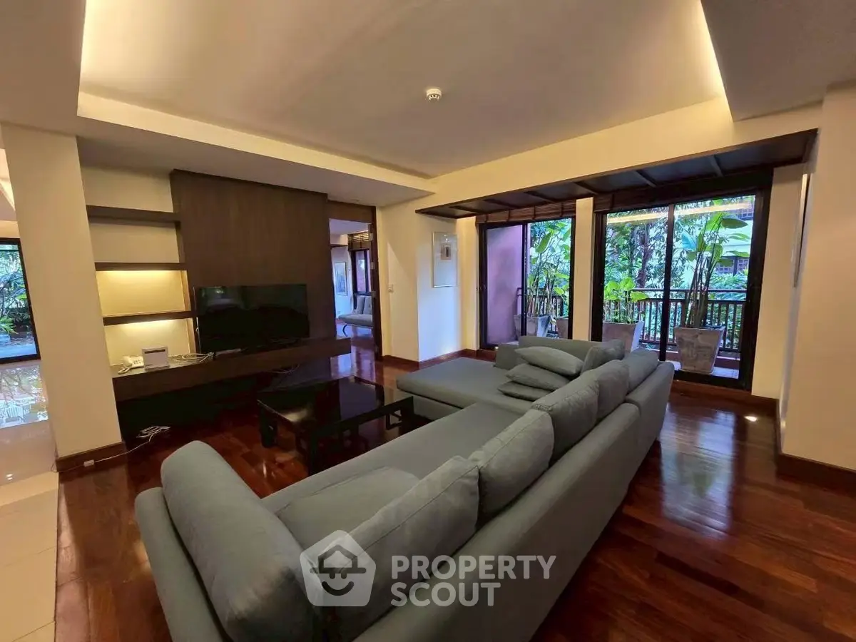 Spacious living room with modern sofa and lush garden view, perfect for relaxation.