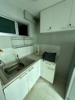 Compact kitchen with white cabinets and stainless steel sink, ideal for small apartments.