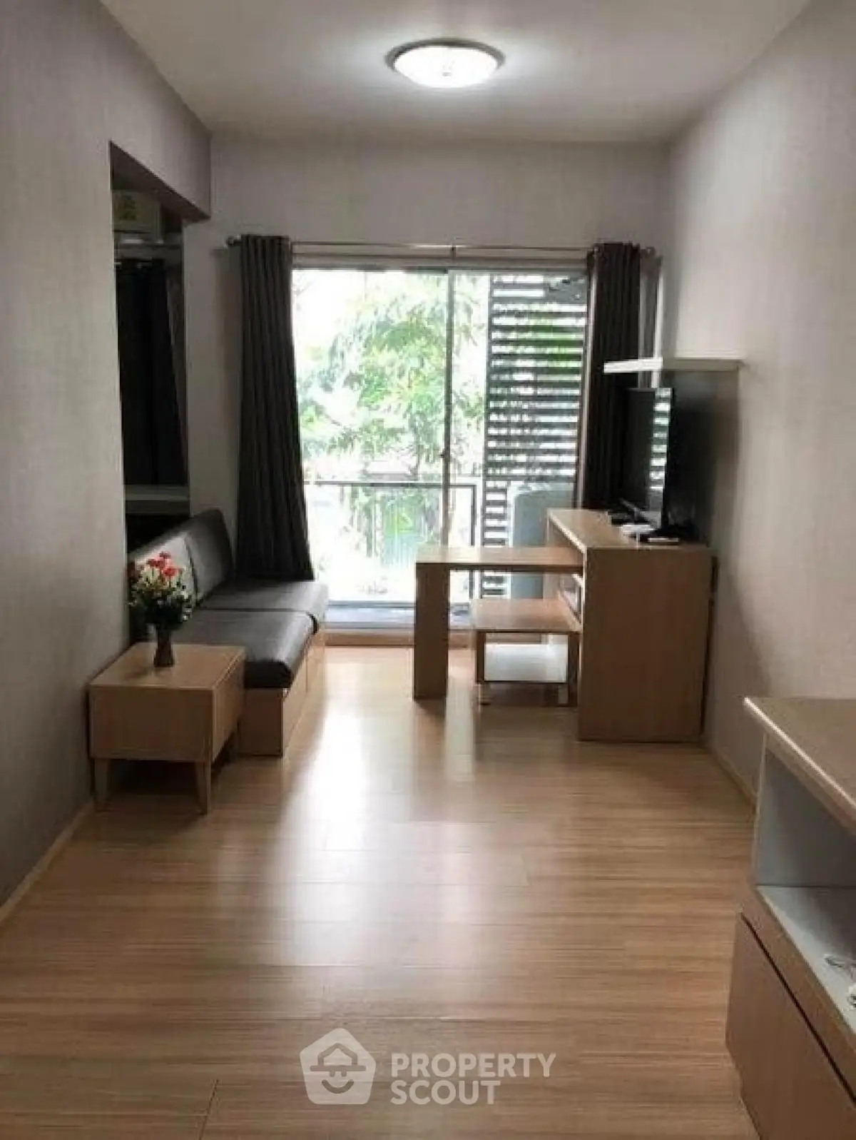 Modern living room with sleek furniture and large window offering natural light and garden view.