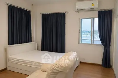 Cozy bedroom with air conditioning and large window offering natural light and serene views.