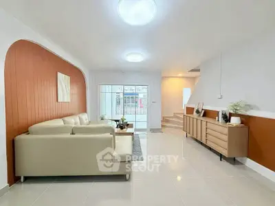 Modern living room with stylish decor and natural light, featuring a cozy beige sofa and sleek wooden furniture.