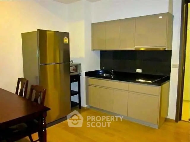 Modern kitchen with sleek cabinets and stainless steel fridge in a cozy apartment.