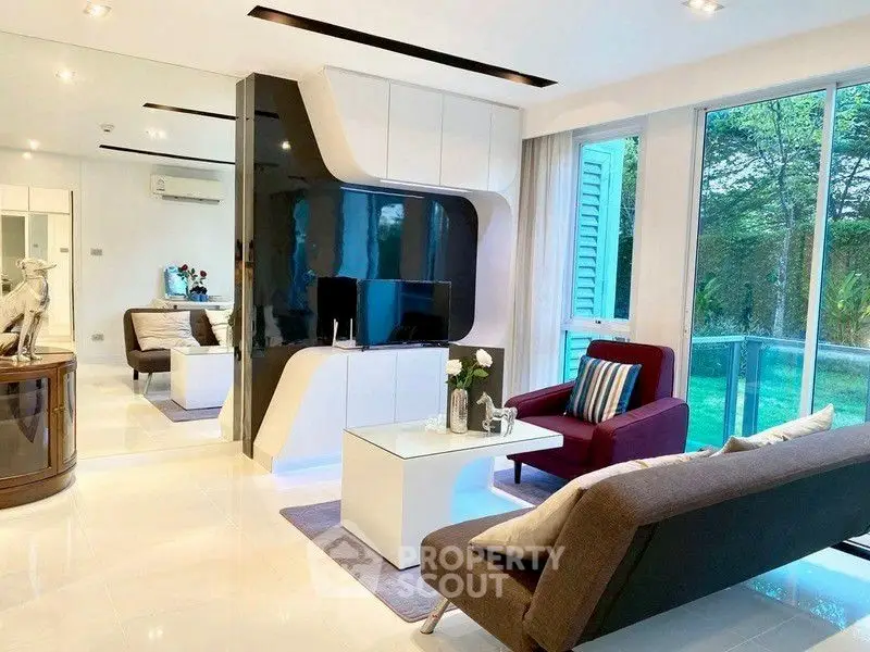 Modern living room with sleek furniture and large windows overlooking greenery.