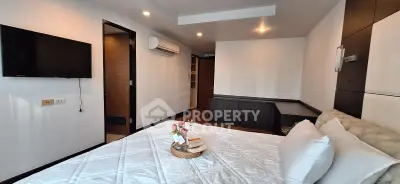 Modern bedroom with wall-mounted TV and cozy bed in stylish apartment.