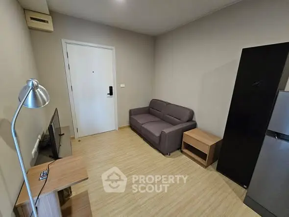 Cozy living room with modern sofa and sleek TV setup in compact apartment.