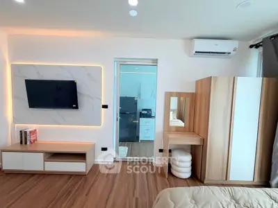 Modern bedroom with stylish furniture and wall-mounted TV, featuring elegant wood flooring and air conditioning.