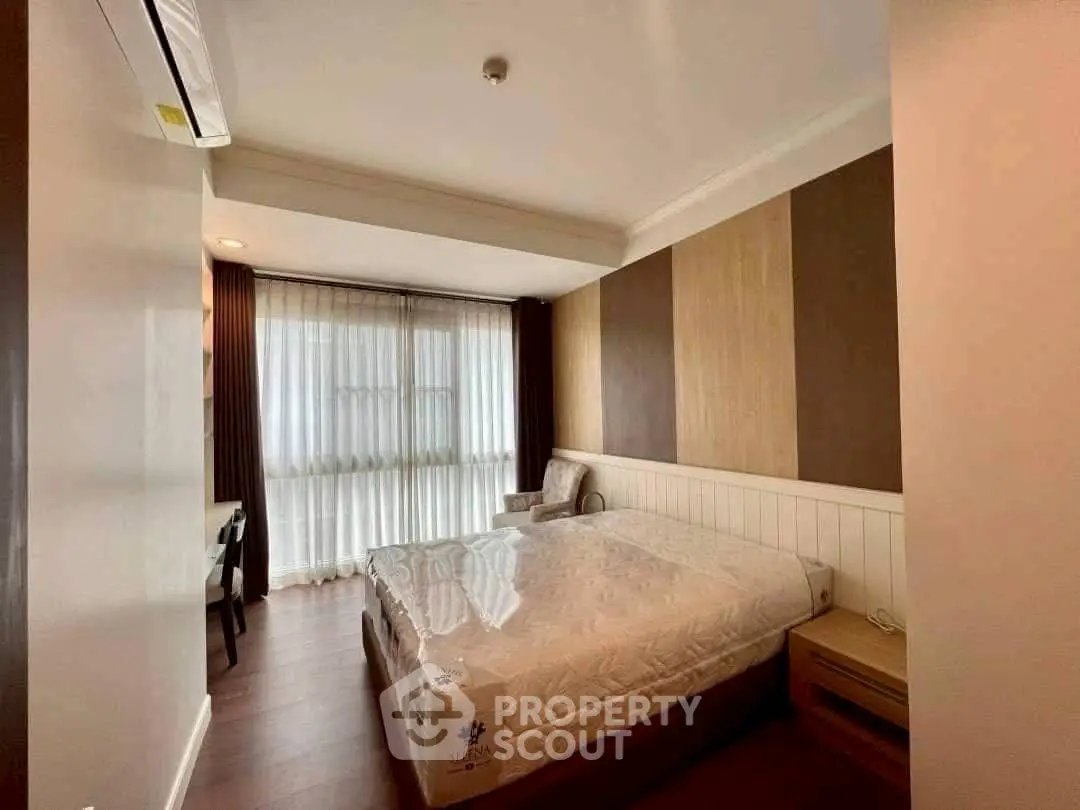 Spacious bedroom with modern decor and large window in a stylish apartment.