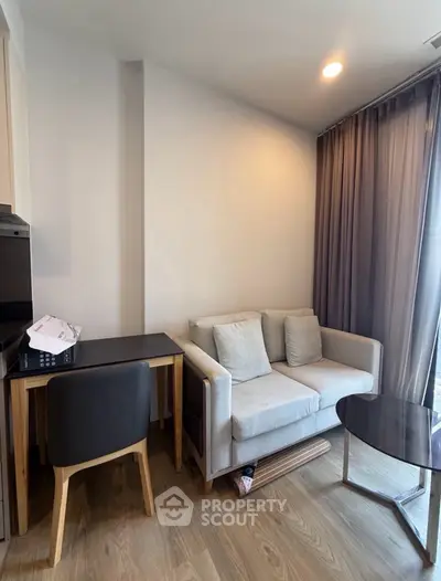 Cozy living room with modern sofa and study desk, featuring elegant curtains and wooden flooring.
