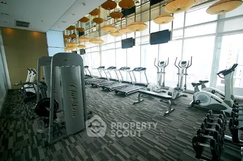 Modern gym with state-of-the-art equipment and large windows in luxury residential building.