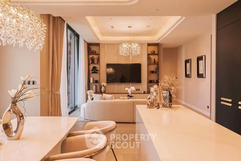 Luxurious modern living room with elegant decor and open layout, featuring a large TV and stylish lighting.