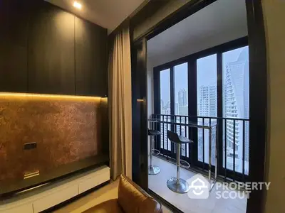 Chic modern kitchen with sleek black cabinetry and golden backsplash, opening onto a cozy balcony with stunning high-rise views.