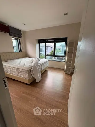 Spacious bedroom with large windows and wooden flooring in modern home