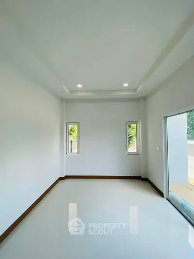 Spacious empty room with large windows and glossy white flooring, perfect for customization.