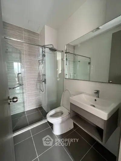 Modern bathroom with sleek design, featuring a glass shower enclosure and contemporary fixtures.