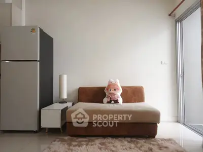 Cozy living room with plush sofa, modern fridge, and natural light from large window.