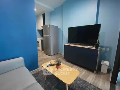 Modern living room with blue walls, flat-screen TV, and sleek kitchen area.