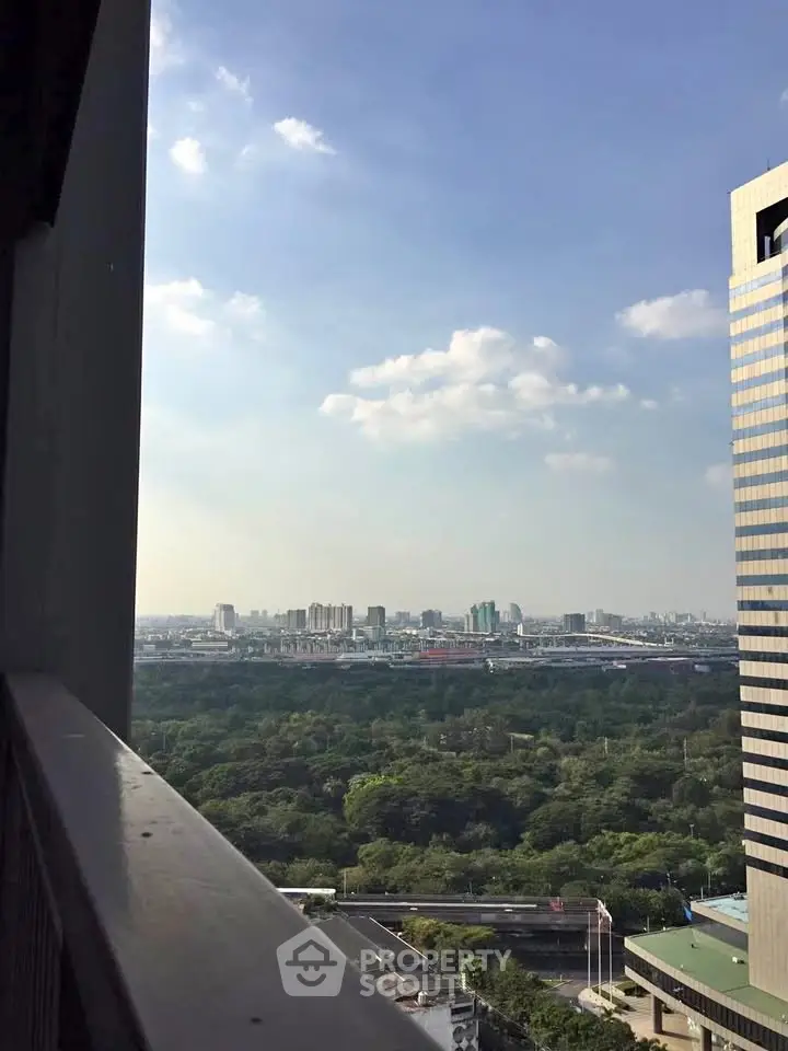 Stunning cityscape view from a high-rise balcony overlooking lush greenery and urban skyline.