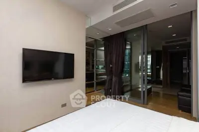 Modern bedroom with wall-mounted TV and glass partition in luxury apartment.