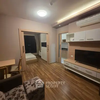 Modern apartment interior with cozy living room and adjacent bedroom, featuring wooden flooring and stylish furniture.