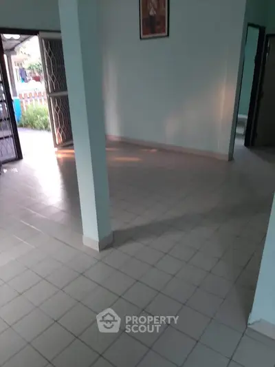 Spacious tiled room with open doors leading to a garden view, perfect for customization.