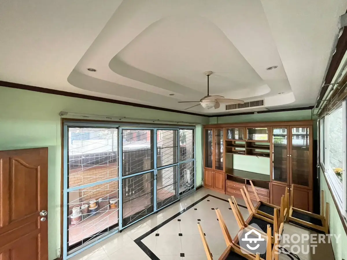 Spacious living room with unique ceiling design, large windows leading to balcony, and ample natural light.