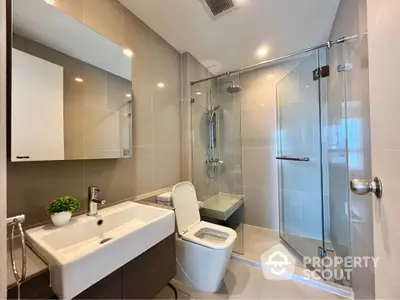 Modern bathroom with glass shower and sleek fixtures in contemporary apartment.