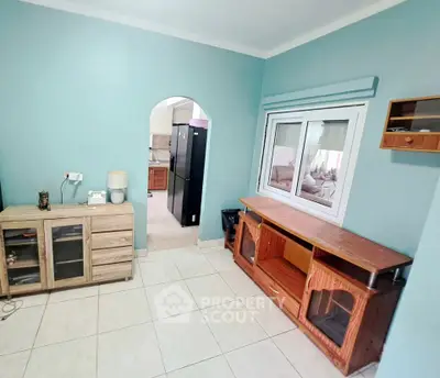 Charming living room with archway and tiled flooring, featuring a cozy interior design and ample natural light.