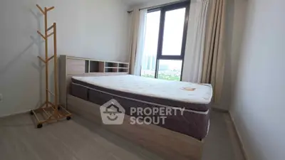 Modern bedroom with large window and stylish bed frame in a high-rise apartment.