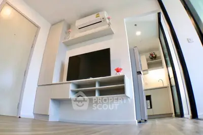 Modern living room with sleek TV setup and open kitchen layout in a stylish apartment.