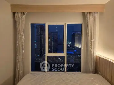 Modern bedroom with large window offering stunning cityscape view at night.